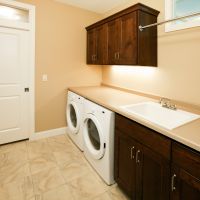 A new house laundry room with front loading washer and dryer and a transom window above the pocket door.